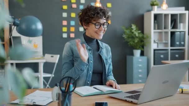 Movimento lento de senhora de negócios alegre falando em chamada de vídeo com laptop no local de trabalho — Vídeo de Stock