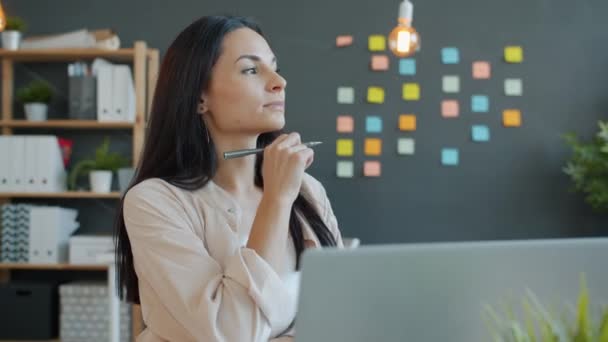 Gyönyörű üzletasszony gondolkodás, majd dolgozik laptop az irodában, srác elfoglalt a háttérben — Stock videók