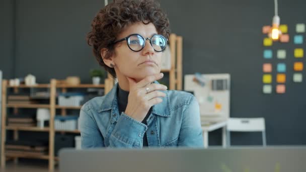 Mujer de negocios seria pensando en resolver el problema de trabajo y luego trabajar con el ordenador portátil en la oficina — Vídeo de stock