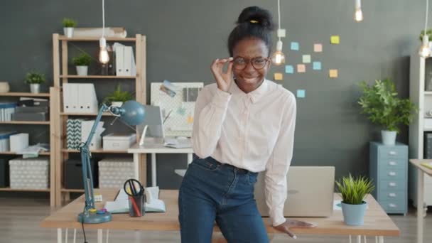 Slow motion portrait of happy mixed race girl wearing glasses standing in office alone smiling