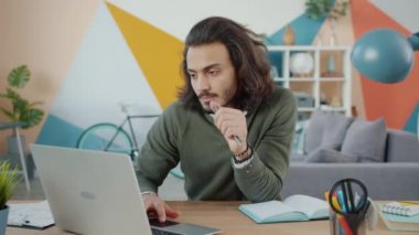 Laptop kullanan yakışıklı bir Arap apartmandan bağımsız olarak çalışıyor.