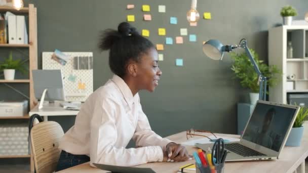 Side view of happy mixed race businesswoman talking to young man during online video call in office — Stock Video