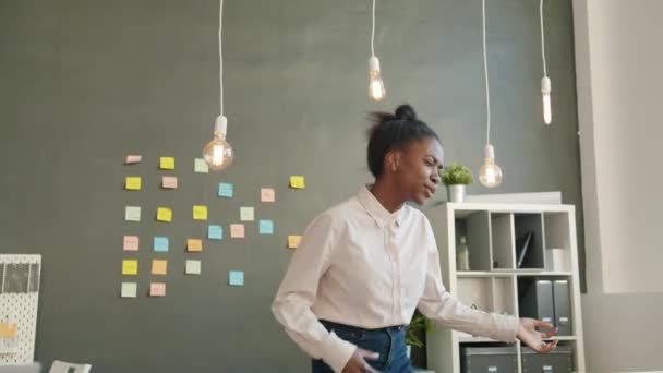 Slow motion van grappig gemengd ras meisje dansen in kantoor kamer met plezier alleen — Stockvideo