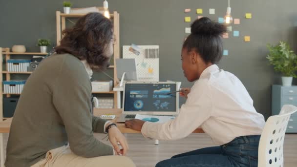 Vidám emberek afro-amerikai lány és arab srác beszél az irodában megvitatása üzleti laptoppal — Stock videók