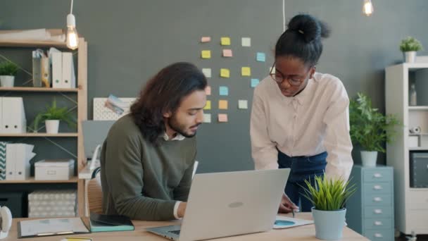 Multietnický tým dívka a chlap mluví a dívá se na papíry a notebook obrazovky na pracovišti — Stock video