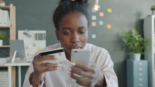 Afro-americká dáma provádí elektronickou platbu on-line pomocí kreditní karty a smartphone v moderní kanceláři — Stock video