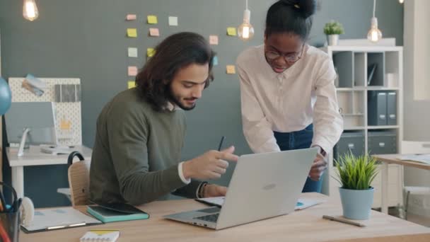 Arabischer Mann und afroamerikanisches Mädchen arbeiten beim Durchsehen von Dokumenten und benutzen Laptop im Büro — Stockvideo