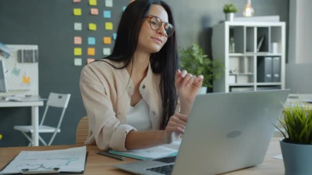 Vrolijke zakenvrouw typen met laptop computer en glimlachen zitten aan het bureau in het kantoor — Stockvideo