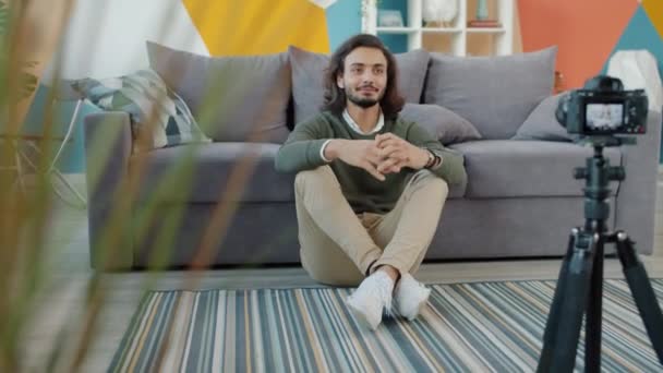 Hombre árabe feliz grabación de vídeo para el blog de Internet hablando y haciendo gestos sentado en el suelo en casa — Vídeos de Stock