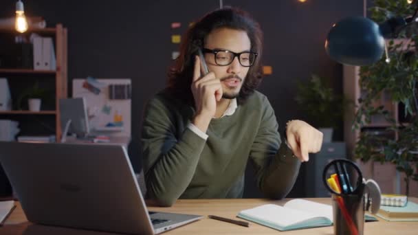 Cámara lenta del hombre árabe que hace una llamada telefónica móvil discutiendo el trabajo en la oficina por la noche — Vídeo de stock