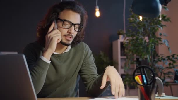 Zeitlupe eines arabischen Mannes in Freizeitkleidung, der spät im Büro arbeitet und auf dem Handy spricht — Stockvideo