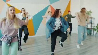 Modern hip-hop stüdyosunda dans eden neşeli öğrenciler içeride birlikte eğleniyorlar.