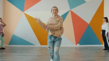 Gülümseyen gençler stüdyoda modern danslar yapıyor birlikte eğleniyorlar.