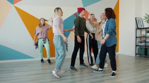 Lento movimiento de los jóvenes bailarines haciendo choca-cinco hablando y sonriendo después de entrenar en el estudio — Vídeos de Stock