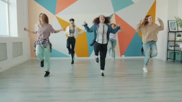 Радостные девушки и парни танцуют в танцевальной студии, изучая современные движения — стоковое видео