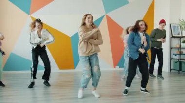 Modern hip-hop sınıfında dans eden aktif gençler kollarını ve bacaklarını oynatıp eğleniyorlar.