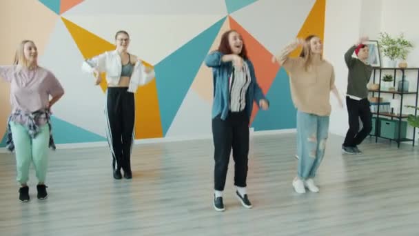 Powolny ruch radosnych nastolatków tańczących w studiu tańca współczesnego skaczących ramionami — Wideo stockowe