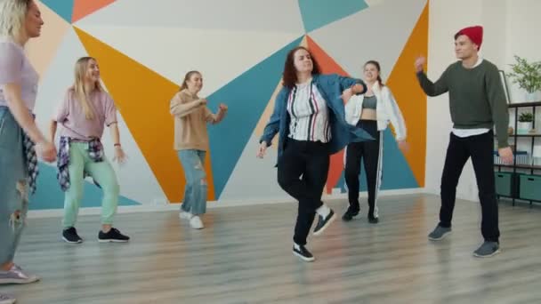 Творческие молодые девушки и парни развлекаются в танцевальной студии — стоковое видео