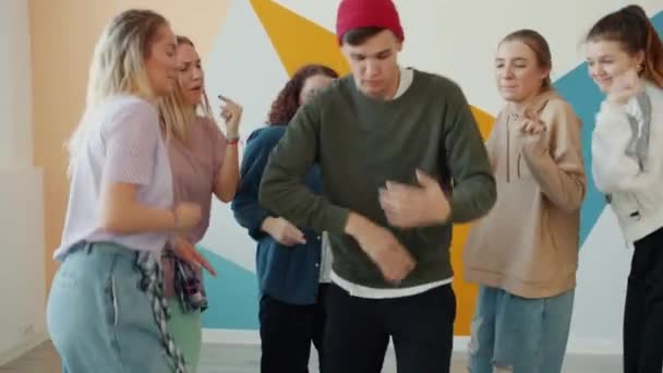 Alegre chico bailando en estudio mientras niñas moviéndose alrededor disfrutando de rendimiento — Vídeo de stock