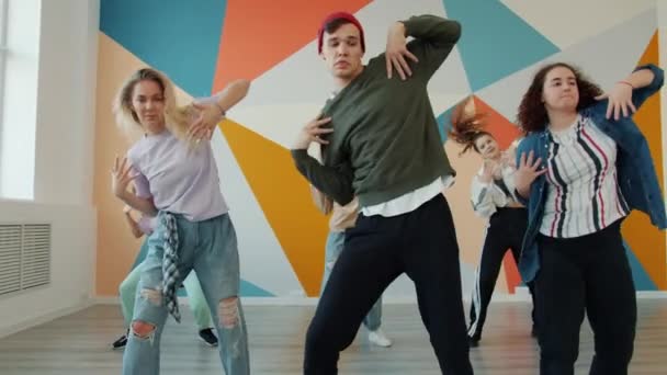Творческие девушки и парни танцуют в современной студии, тренируясь в помещении — стоковое видео