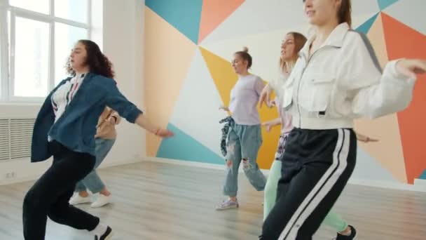 Медленное движение эмоциональных девушек, исполняющих современный танец в современной студии — стоковое видео