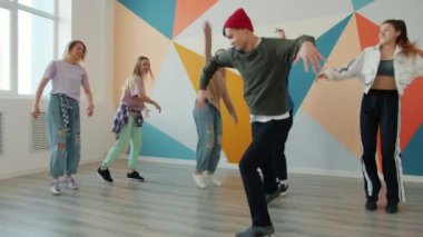 Dans eden hip-hop stüdyosunda dans eden neşeli gençlerin yavaş çekimleri moda giysiler giyiyor.