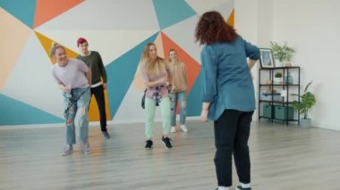 Neşeli gençler stüdyodaki profesyonel dansçılardan dans hareketleri öğreniyor.
