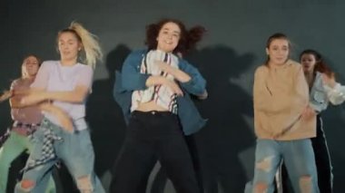 Karanlık dans salonunda dans eden bir grup öğrenci yaratıcı dans gösterisi yapıyorlar.