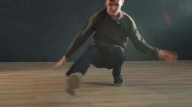 Genç hippi adam karanlık odada break dans gösterisi yapıyor. Dansın tadını çıkarıyor.