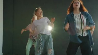 Profesyonel dansçılar kapalı alanda aydınlanmış sahnede güzel bir dans gösterisi sergiliyorlar.