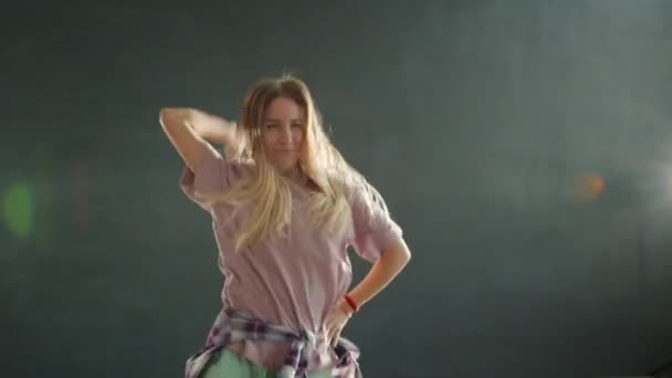 Słodkie nastolatek blondynka taniec na ciemny scena z szary bokeh tło — Wideo stockowe