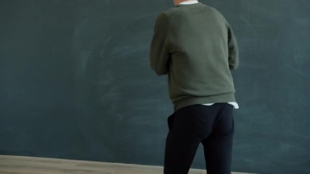 Joven chico hipster bailando hip-hop en estudio moderno con paredes grises con estilo — Vídeo de stock
