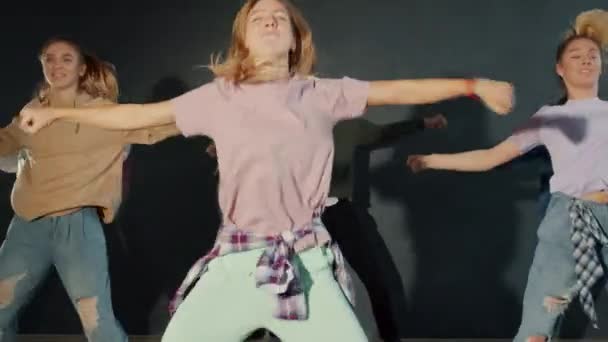 Retrato de adolescentes atractivos bailando en el escenario dentro de la oscuridad iluminada — Vídeo de stock