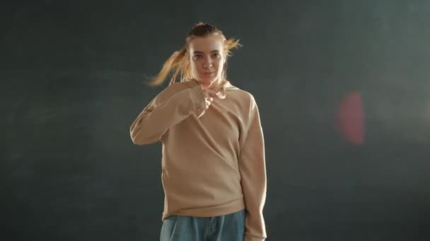 Zeitlupe einer schönen jungen Frau, die drinnen auf grauem Hintergrund tanzt — Stockvideo