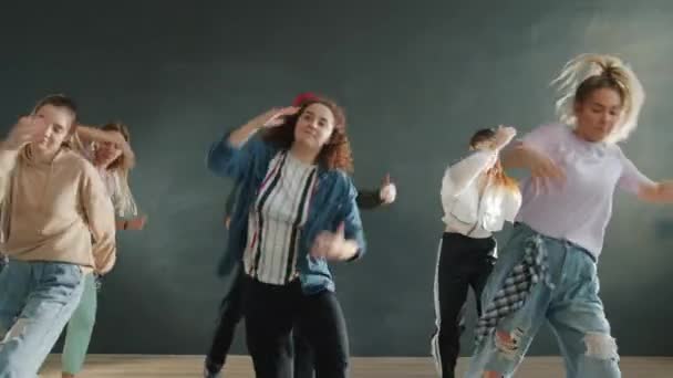 Zpomalený pohyb tanečního týmu vystupujícího společně v interiéru a užívající si hudbu — Stock video