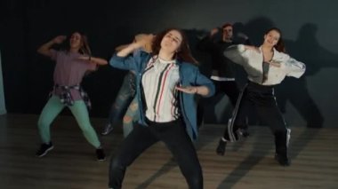 Karanlık dans salonunda dans eden bir grup gencin ağır çekimleri.