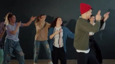 Karanlık odada dans eden neşeli öğrenci dansçıların portresi.