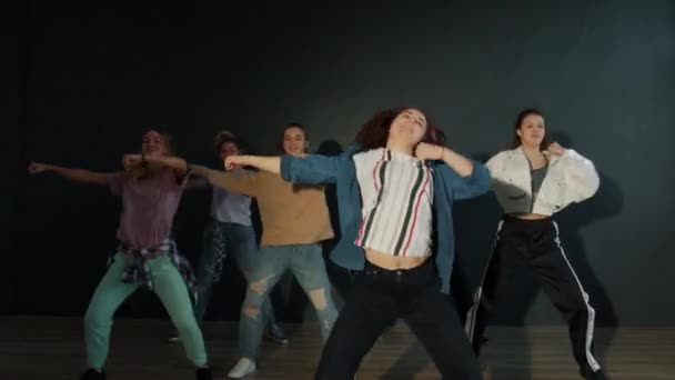 Slow motion van gelukkige creatieve tieners dansen in donkere kamer uitvoeren van moderne show — Stockvideo