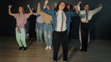 Bir grup genç dansçı karanlık salonda modern dans gösterisi yapıyorlar.