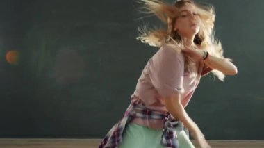 Karanlık stüdyoda dans eden güzel bir genç kızın ağır çekimleri.