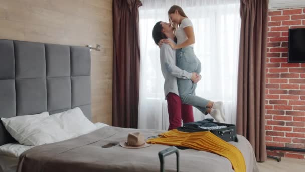 En lykkelig mann som holder en kvinne i hendene på et hotellrom og uttrykker kjærlighet – stockvideo