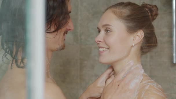 Esposo y esposa lavándose en la ducha y besándose divirtiéndose con espuma de jabón — Vídeos de Stock