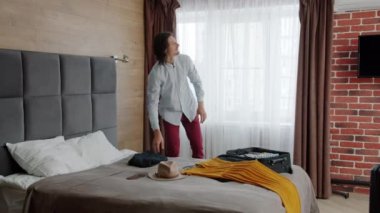 Otelde bavulunu boşaltan ve güzel bir kadını öpüp kucaklayan adamın ağır çekimde çekimi.