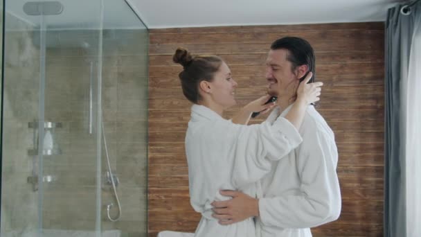 Fiatal nő fésülködő férfi haj után zuhany és csók, emberek viselnek fürdőköpeny — Stock videók