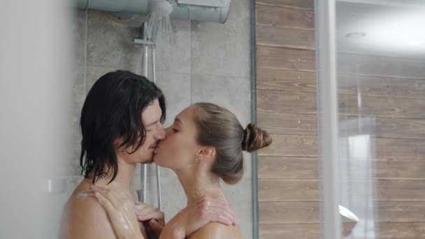 Portrait of beautiful young couple kissing and hugging washing in shower together — Stock Video