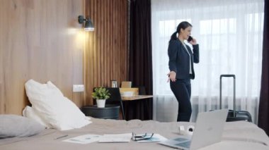 Güzel bir iş kadınının portresi otel odasında cep telefonuyla konuşuyor.