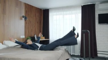 Genç ve çekici bir iş kadınının otel yatağına düşmesi ve dinlenmenin keyfini çıkarması.