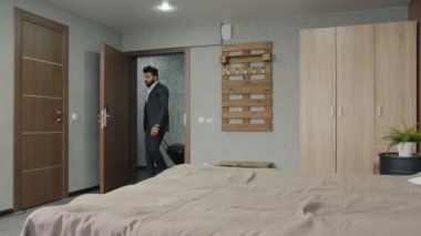 Genç Arap işadamı, takım elbisesiyle otel odasına giriyor ve dinleniyor.