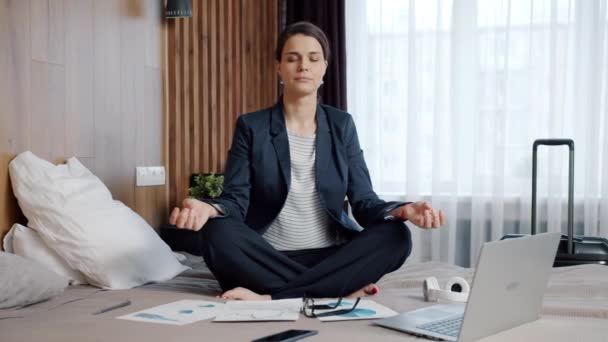O femeie de afaceri care se relaxează în lotus pozează pe patul de hotel meditând bucurându-se de odihnă — Videoclip de stoc