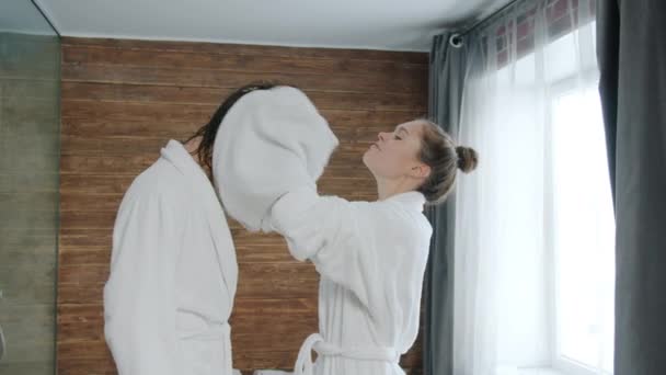 Молодая женщина в халате сушит мужчин влажные волосы полотенцем, то поцелуи в отеле — стоковое видео